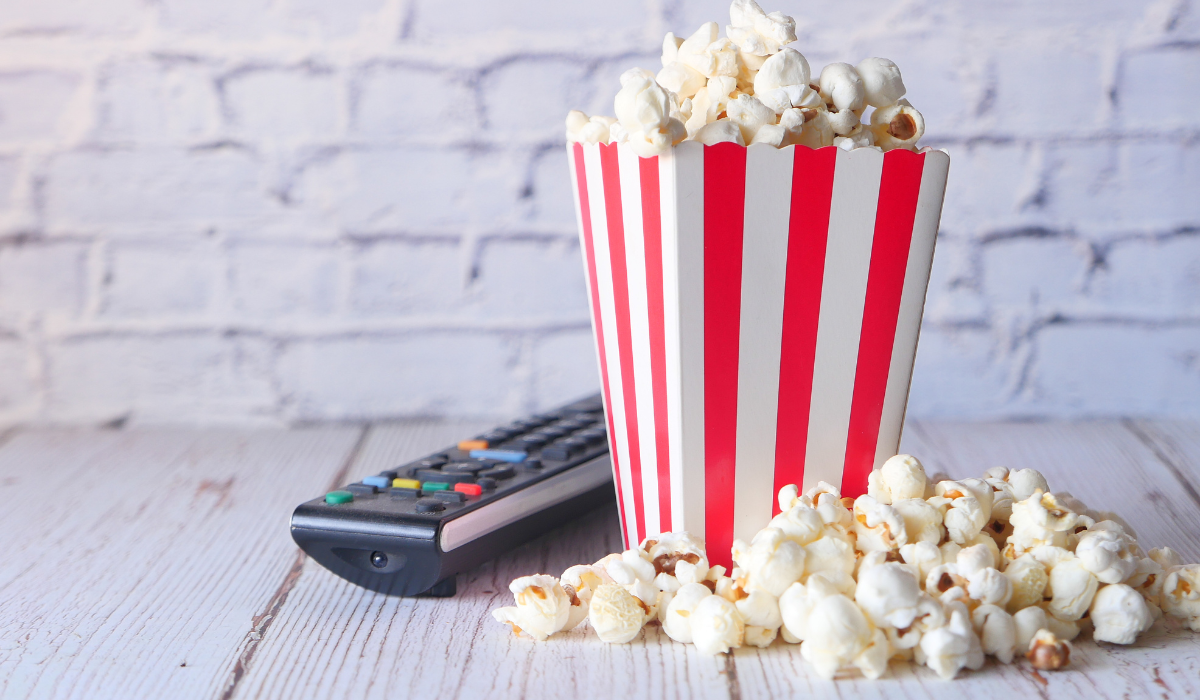 Bol de pop-corn, box et télécommande devant un mur de briques