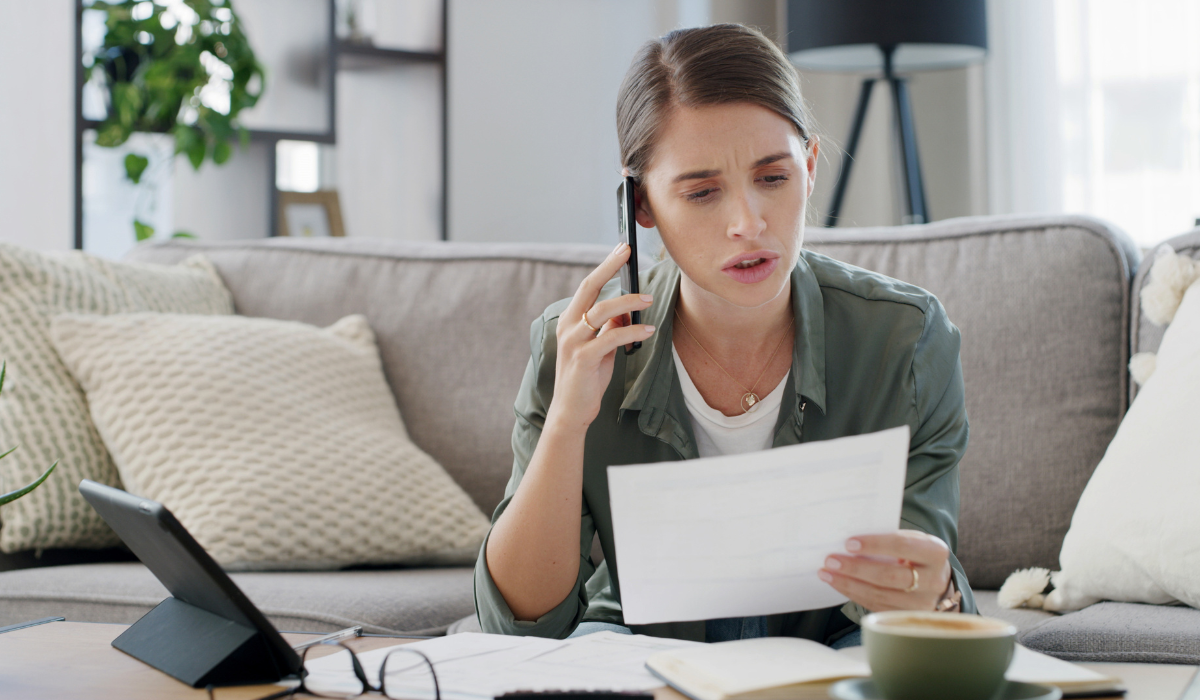 Femme au téléphone, l'air inquiet, en train de lire une facture